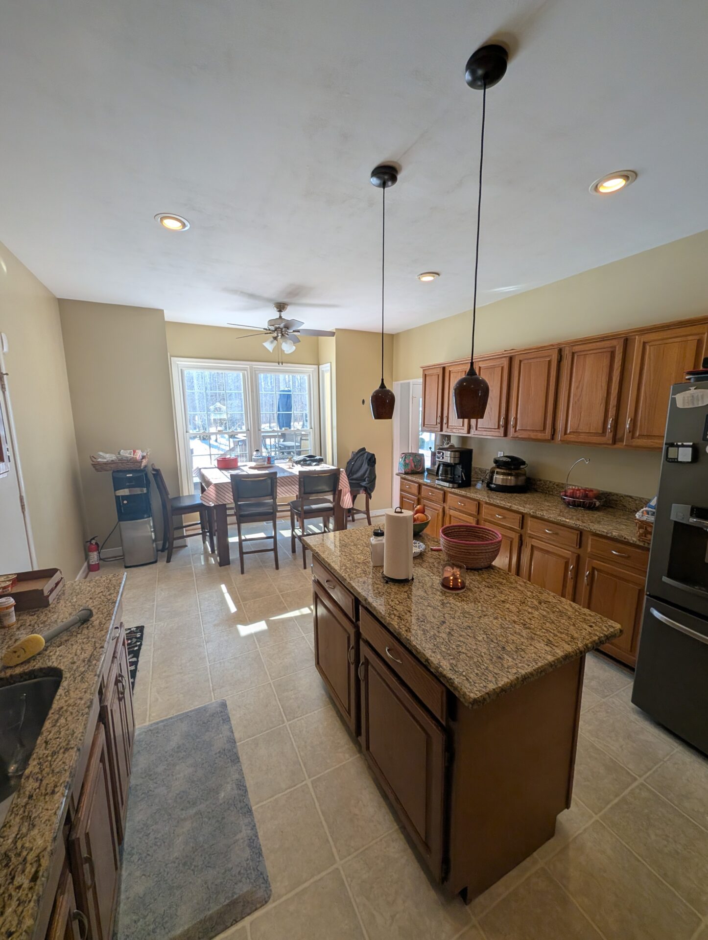 Before: dated honey oak kitchen with granite countertops and beige tile floor in Rockville MD