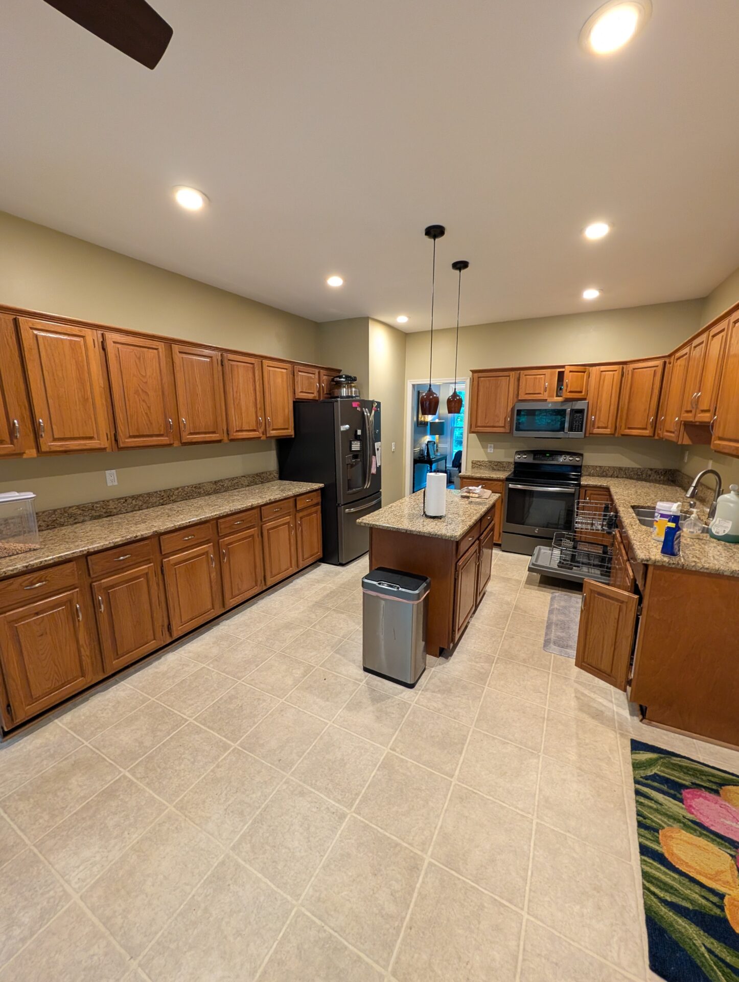 Before: long run of oak cabinets and speckled granite counters prior to kitchen remodel