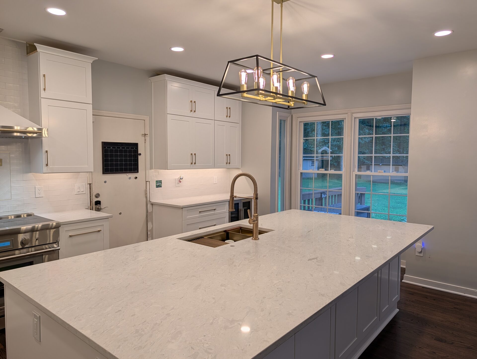 Completed quartz kitchen island with brass faucet and black and brass lantern pendant
