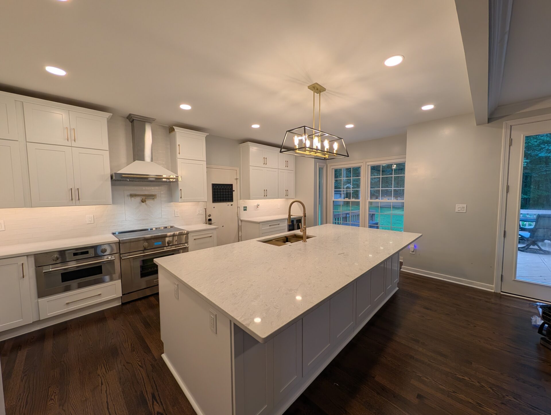 Finished kitchen remodel in Montgomery County MD with white shaker cabinets, quartz island and dark hardwood floors