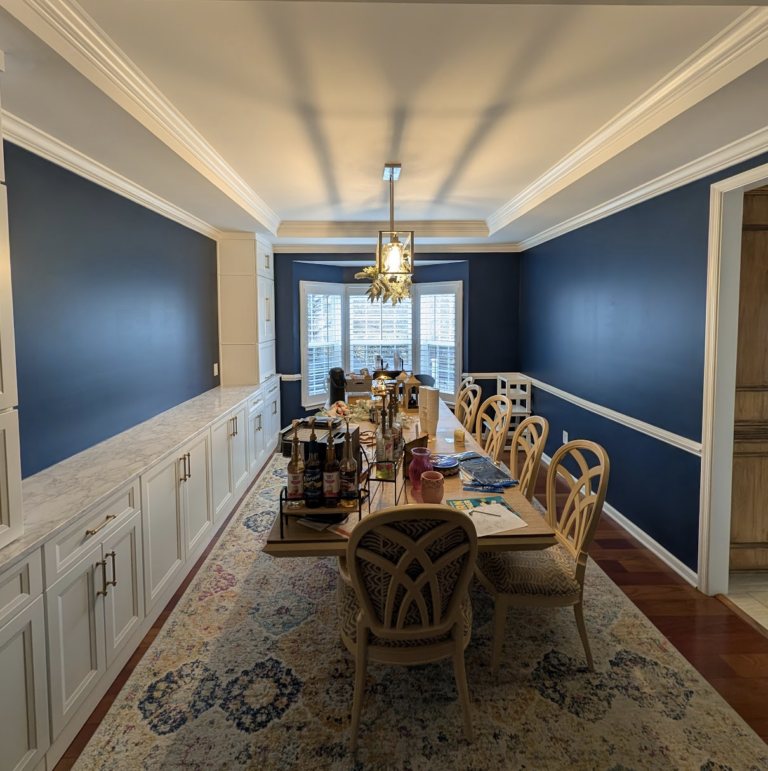 Dining room after renovation, with navy walls, custom white built-in cabinetry and refinished hardwood floors