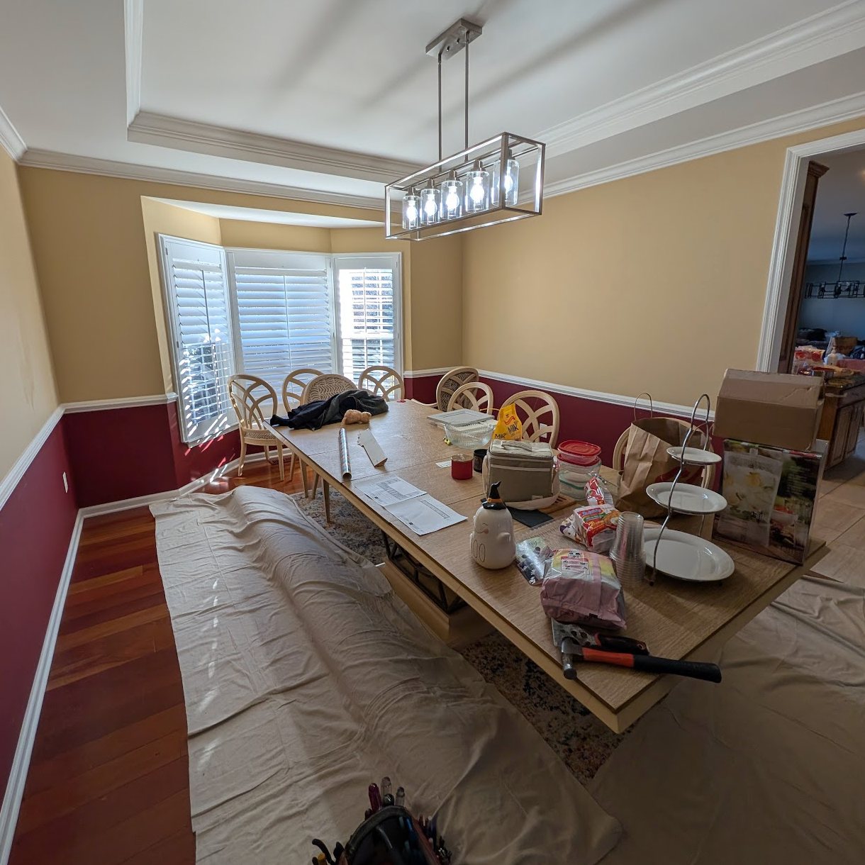 Dining room before renovation, with tan and red walls, no built-in storage and the room covered for work