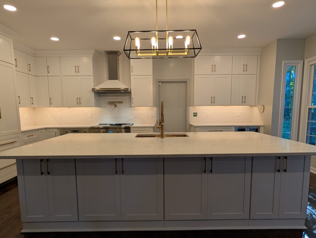 Remodeled Rockville kitchen island facing the range wall with a white range hood, pot filler and cabinets to the ceiling